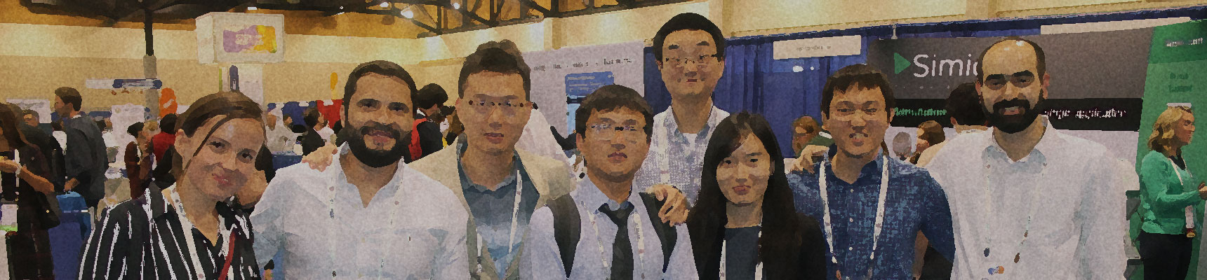 A group of eight male and female students standing together and smiling in an exhibition hall.
